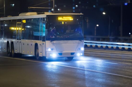 Passenger bus driving on highway at night.